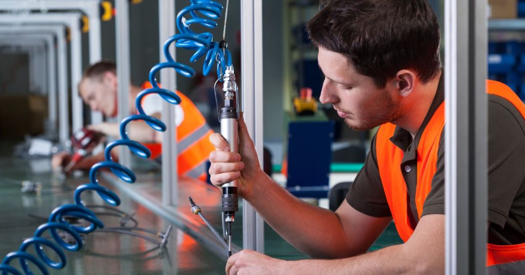 Produktionsarbejder i orange vest på fabrik